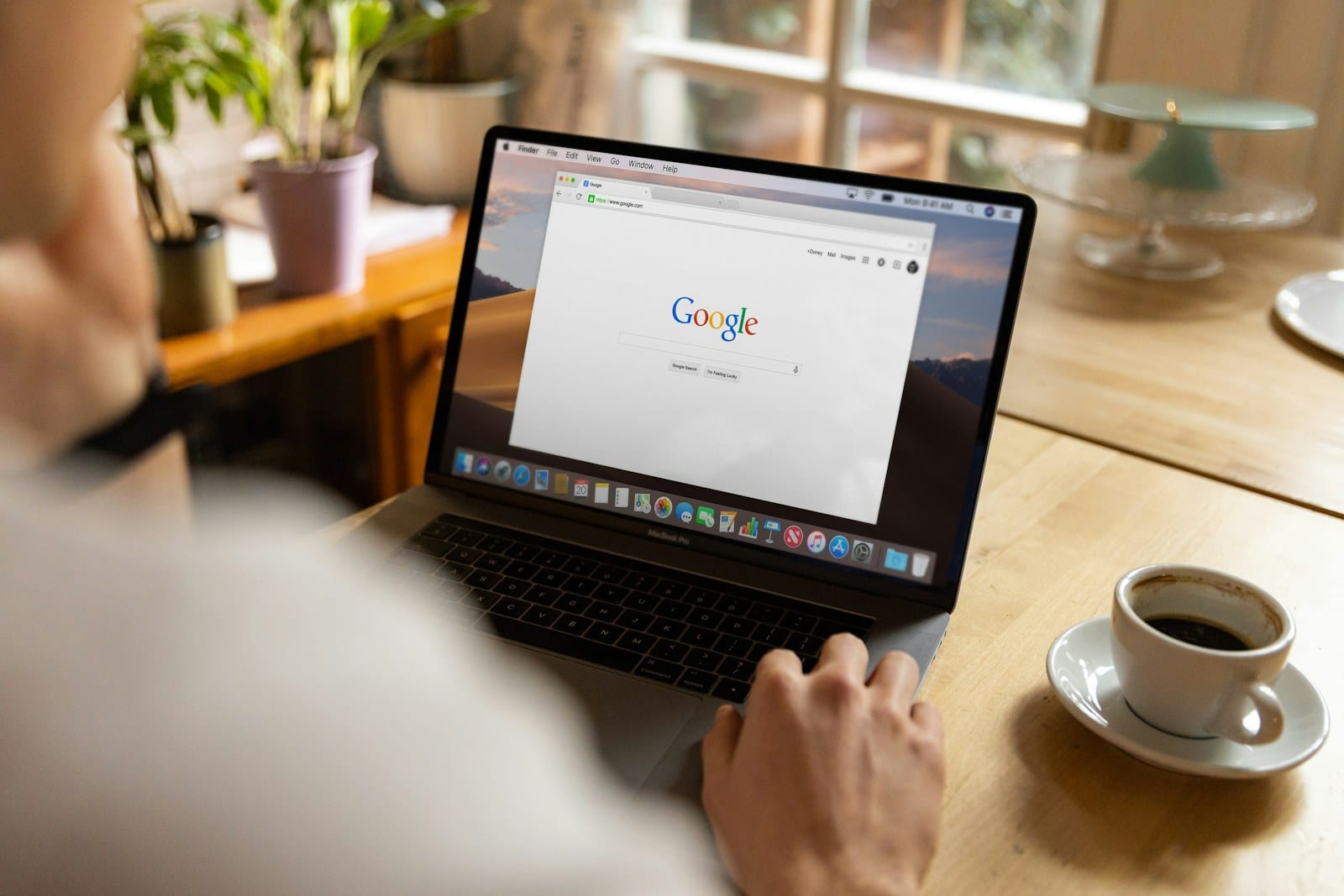 A person using a MacBook with the Google search page open.